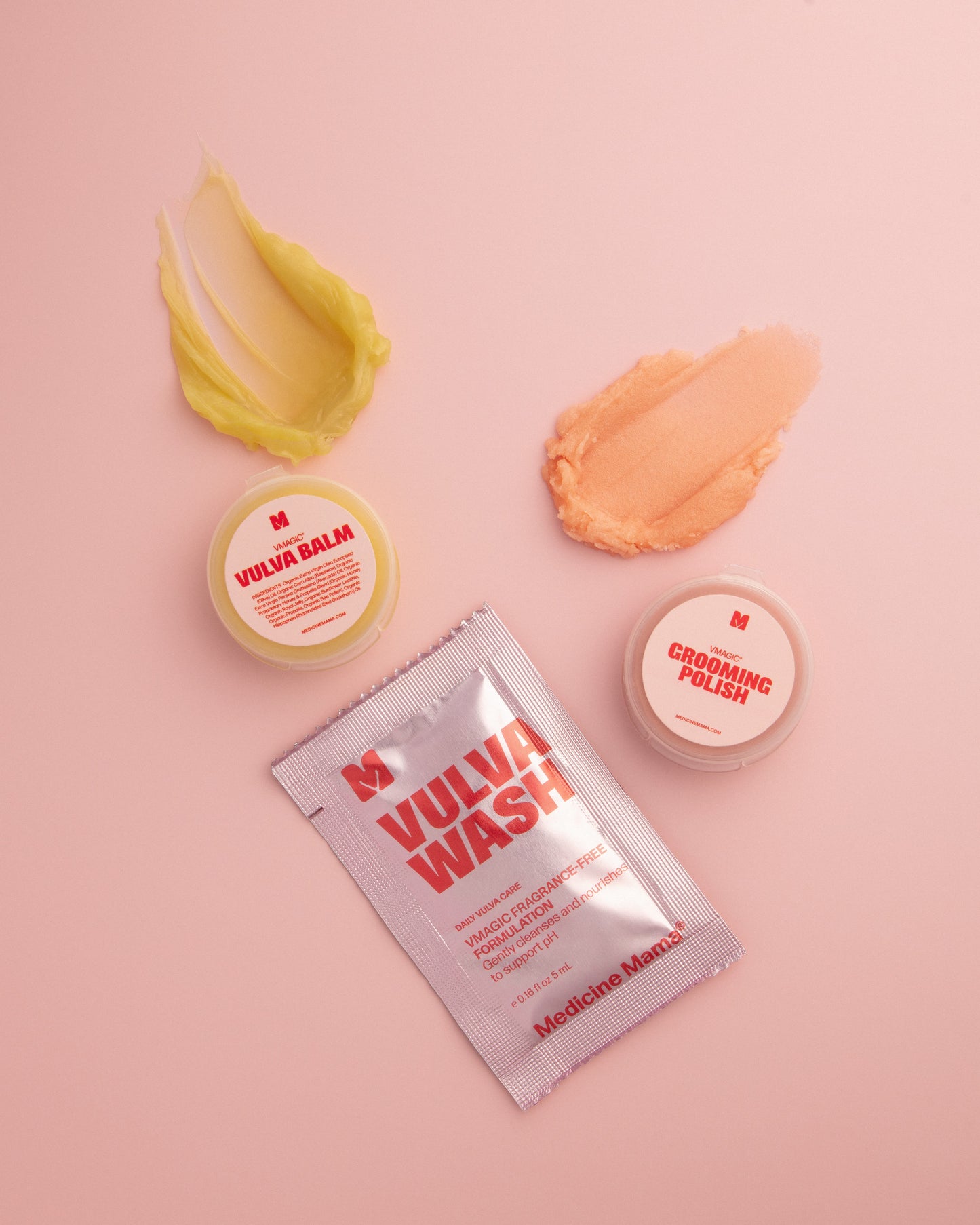 Three products from the VMAGIC® Discovery Kit—Vulva Wash, Vulva Balm, and Grooming Polish—rest on a pink background with two cream swatches displayed above them.