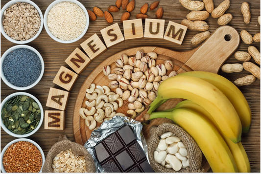 Magnesium-rich foods including nuts, seeds, bananas, and dark chocolate arranged around wooden blocks spelling MAGNESIUM