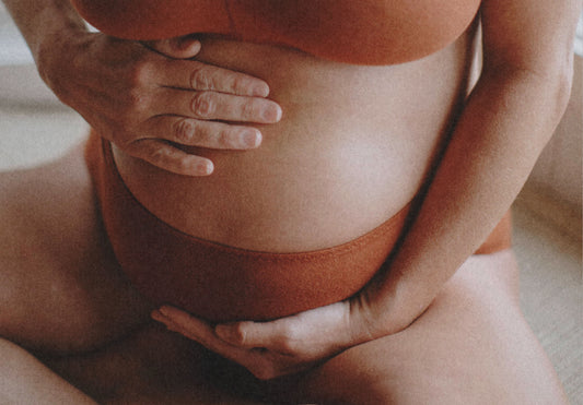 Pregnant woman applying vulvar balm and stretch mark balm