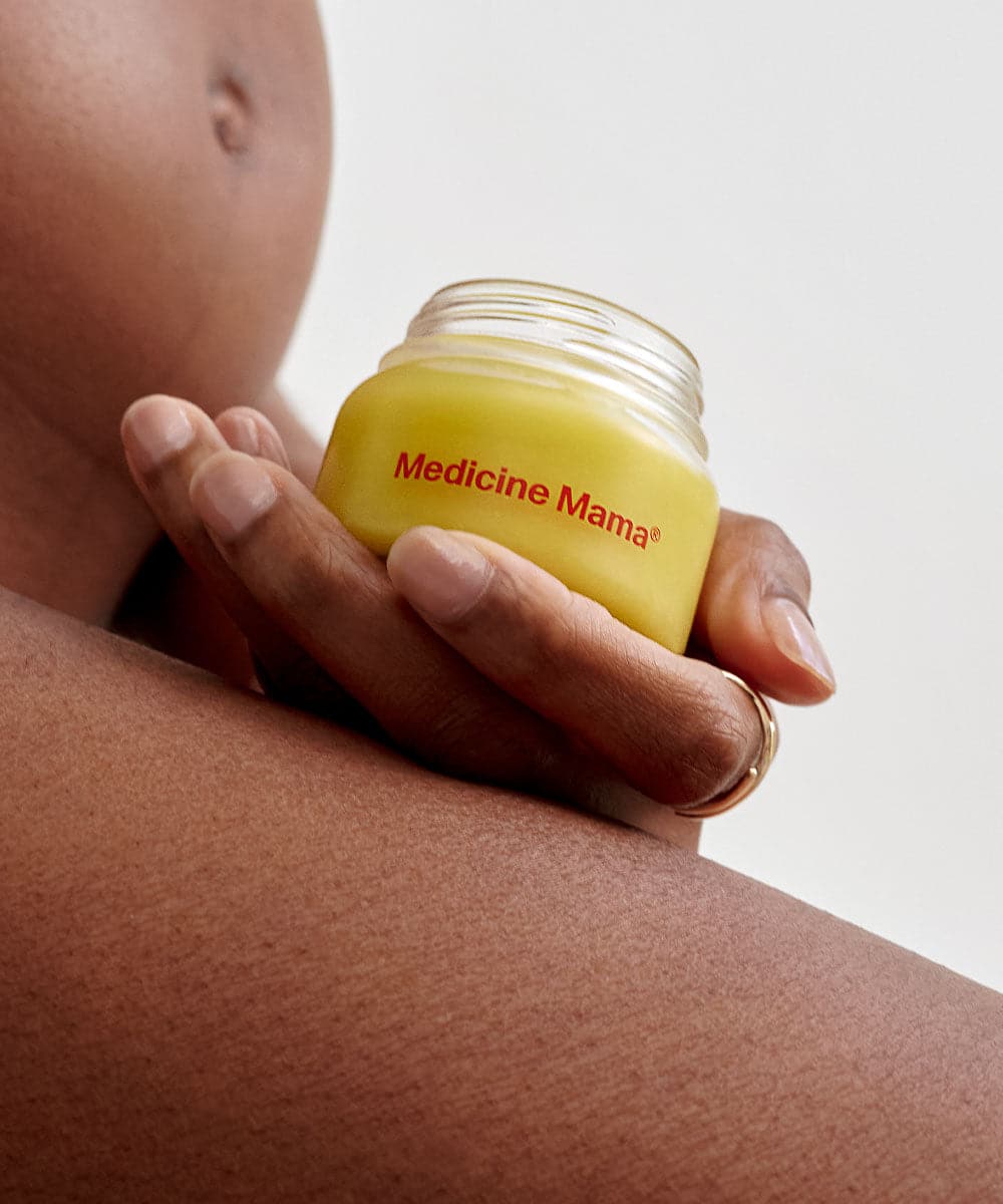A pregnant woman holding a bundle of Medicine Mama's VMAGIC® Daily Care Duo: Balm & Wash - Preorder ships 1/17/24 for her vulva care routine.